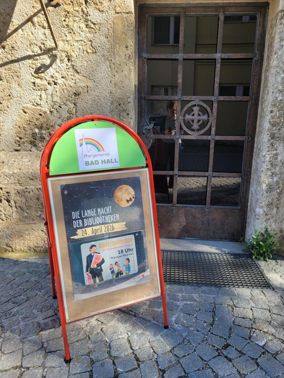 Eingang Pfarrsaal mit Kundenstopper und Plakat